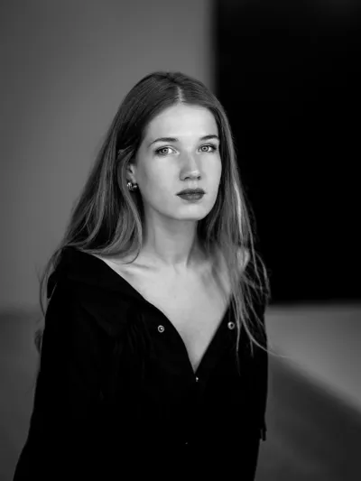 Black-and-white portrait of a young woman with long straight hair in a dark open-collared shirt