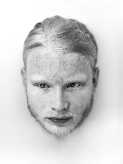 Black-and-white high-key close-up of a fair-haired freckled man's face on a white background