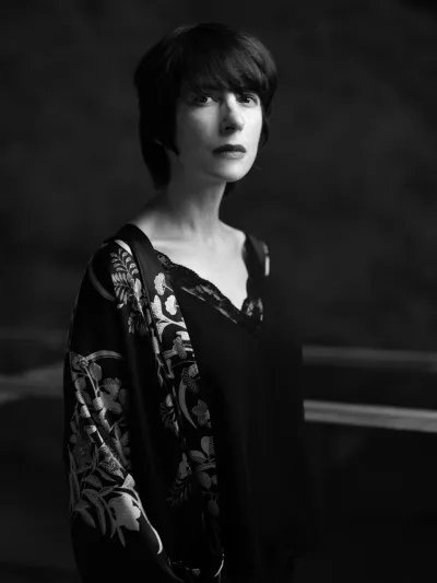 Black-and-white portrait of a woman with a dark bob and floral-embroidered sleeve
