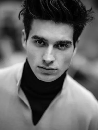 Black-and-white portrait of a young man in a cream sweater over a black turtleneck