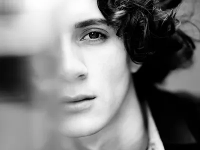 Black-and-white close-up of a young person's face with dark curly hair and foreground blur