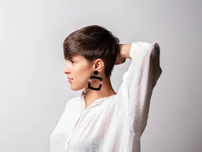 Black-and-white profile of a woman with a pixie cut and large square earring