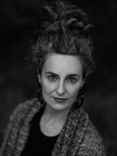Black-and-white studio portrait of a woman with a voluminous curly updo and drop earrings